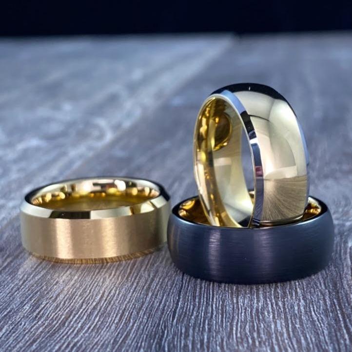 Three Men's Wedding Bands featuring a black domed ring, a gold ring and The Doubloon: A Gold Tungsten Men's Wedding Band with Silver Edging and Domed Design