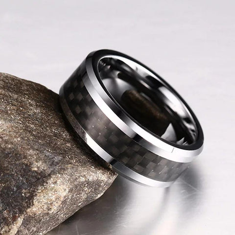 Tungsten Men's Wedding Band with Black Carbon Fiber Inlay and Beveled Edges Leaning Against Rock | The Executive