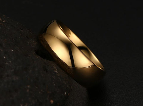 Image of Tungsten Men's Wedding Band with a Domed Design in Gold, Leaning Against Rock  | The Genesis