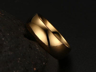 Tungsten Men's Wedding Band with a Domed Design in Gold, Leaning Against Rock  | The Genesis